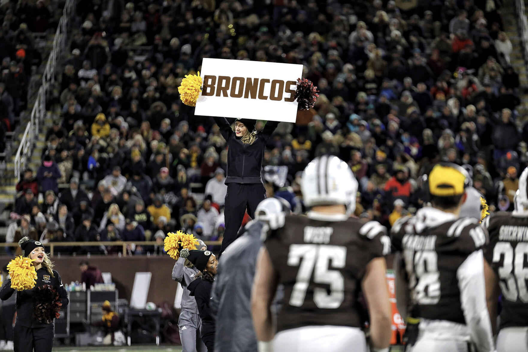 A member of the WMU Cheer team displays a 'Broncos' sign.